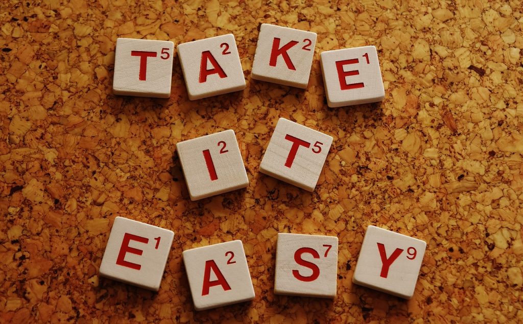 A cork board with scrabble tiles spelling out " take it easy ".