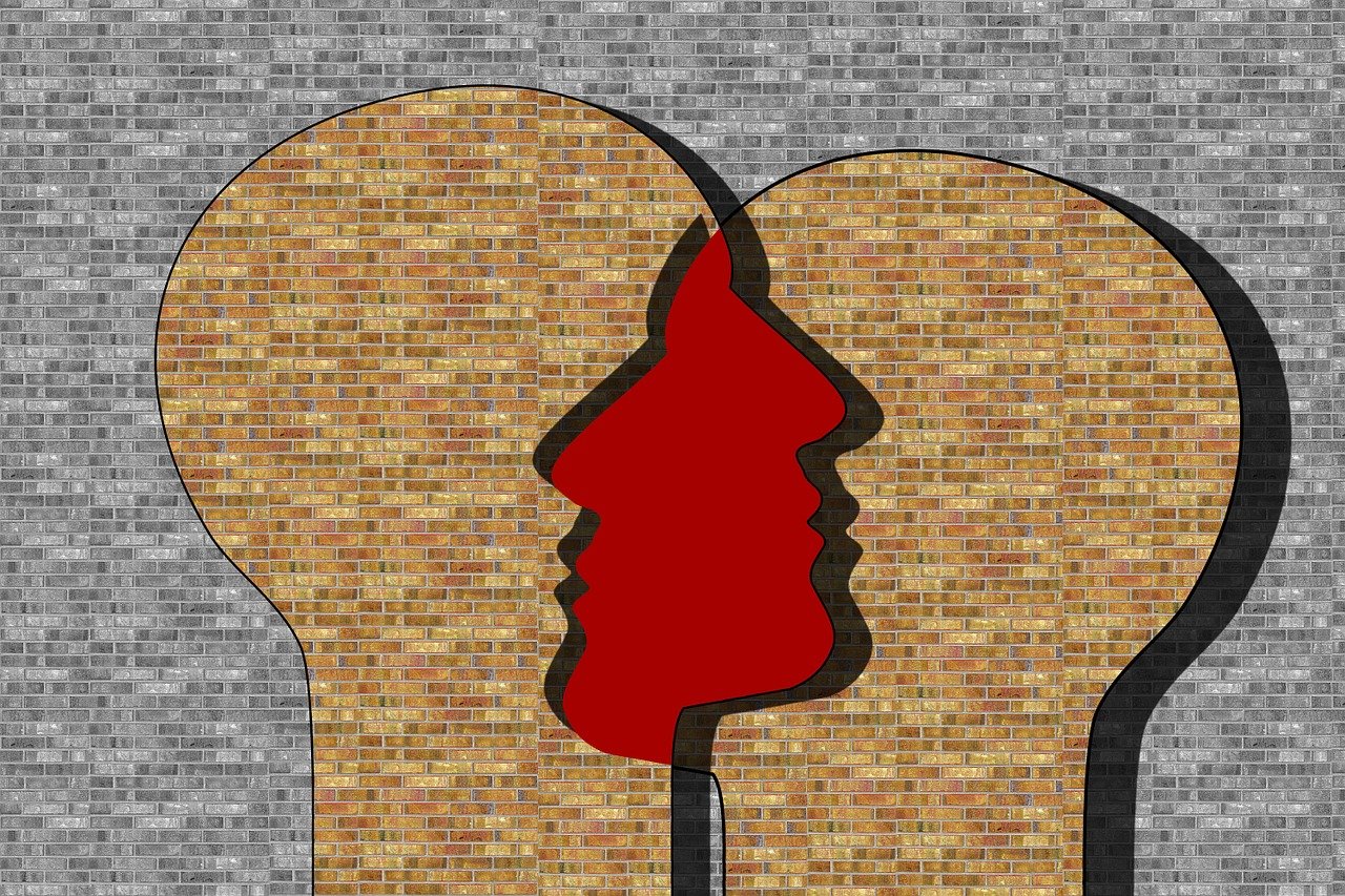 A brick wall with two faces and one has red paint on it.