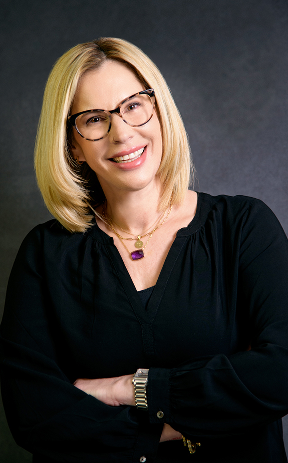 A woman with blonde hair wearing glasses and black shirt.